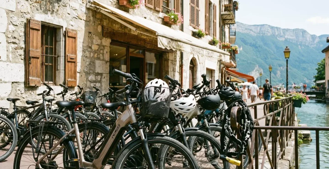 Rangée de vélos électriques prêts à louer dans une boutique de location à Annecy, avec des casques et des antivols visibles